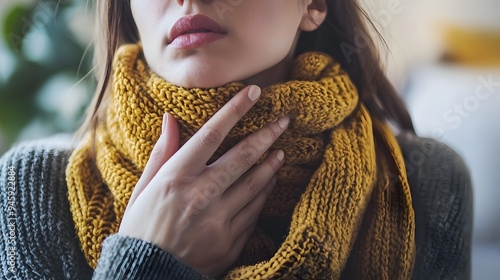 Person with Scarf Around Neck Holding Throat in Discomfort,Showing Symptoms of Illness photo