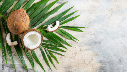 Fresh coconut with tropical leaves on light background, summer holiday vibe. Banner with copy space