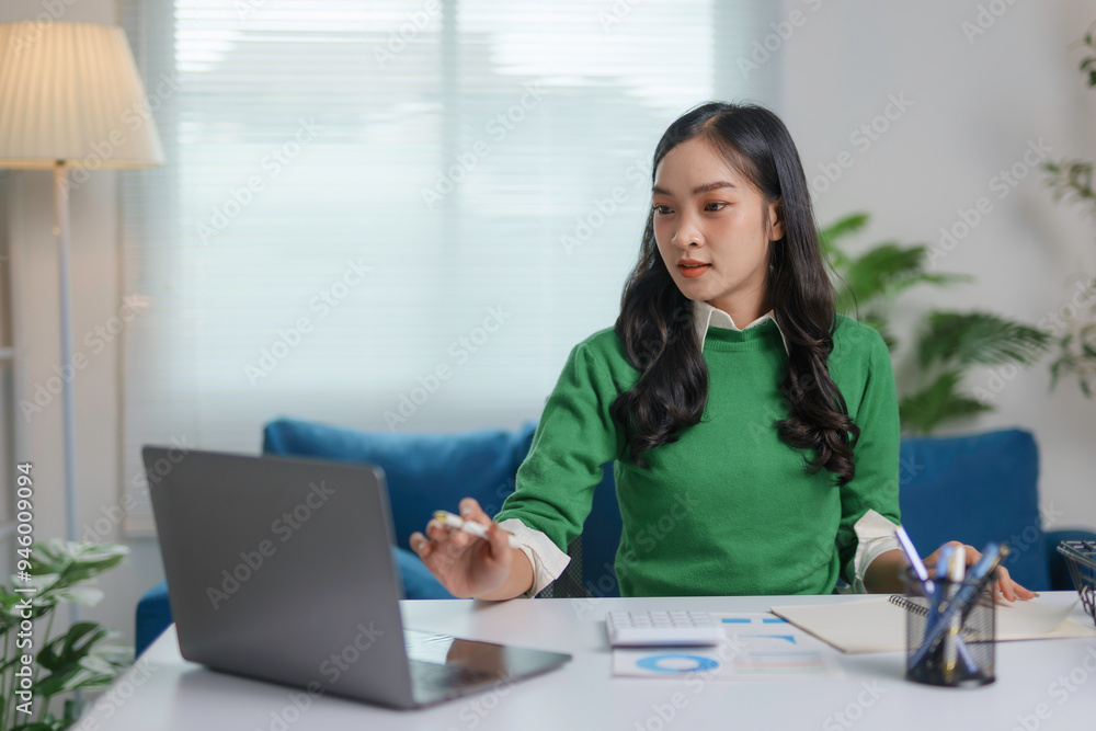 Asian accountant woman working on laptop computer and analyzing financial statement documents with calculator at home office