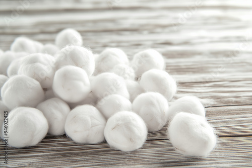 Soft cotton balls scattered on a vintage wooden table with copy space. Natural light. Rustic farmhouse background. 