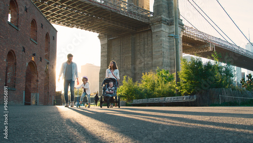 Family Day Out With Mum Pushing Baby In Buggy As They Walk By Brooklyn Bridge In New York City USA