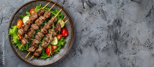 Grilled beef kebabs on sticks served with a fresh vegetable salad on a plate set against a rustic concrete background from above A traditional Middle Eastern Turkish dish kebab with space for text photo