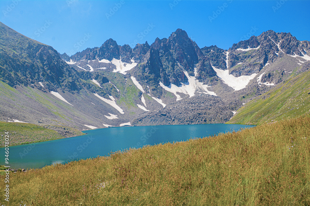 Obraz premium Beautiful natural landscape with high rocky mountains and crystal clear lake. Blue lagoon. Blue lake. Beautiful mountain with lake. Wild flowers