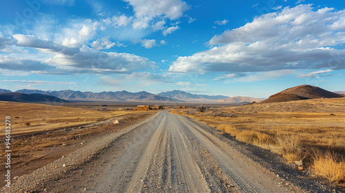 A gravel road crossing a desolate, arid landscape, with the small, remote village visible on the horizon, surrounded by nothing but dry plains and distant mountains