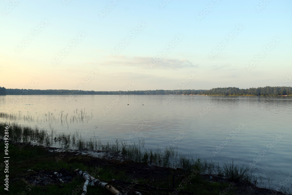 sunset over the lake. A calm surface of water at sunset, with trees and bushes on the horizon sunset over the lake. A calm surface of water at sunset, with trees and bushes on the horizon