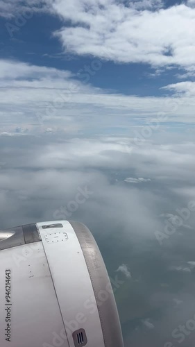 Window view from the passenger in the plane while flying into the fluffy cloud. Selective focus on the engine of the plane flying in the high level in the air with the cloud