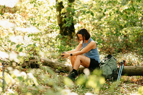 A hiker takes a welldeserved rest on a log, surrounded by lush greenery, fully enjoying natures tranquility photo