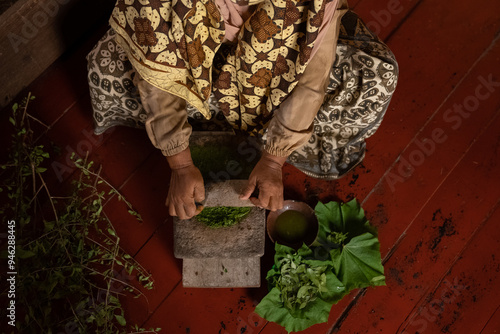 An Asian woman grinds leaves from the henna tree to make henna paste