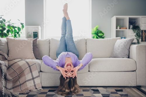 Full length photo of cheerful girl lying couch upside down fooling glasses dressed violet garment spend pastime spacious house indoors room