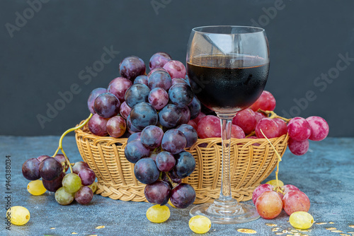 Obraz na płótnie Black grapes on a table, red grapes in a basket and a glass of red wine on the table w salonie