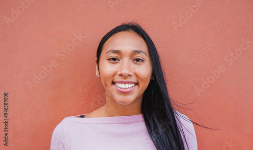 Portrait of native american woman smiling on camera with city wall in background - Indigenous girl outdoor photo