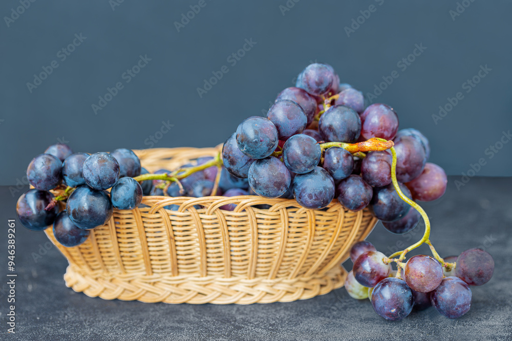 Black grapes in a wicker basket on a table.