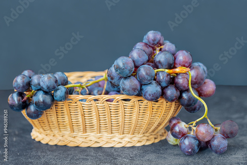 Obraz na płótnie Black grapes in a wicker basket on a table. w salonie