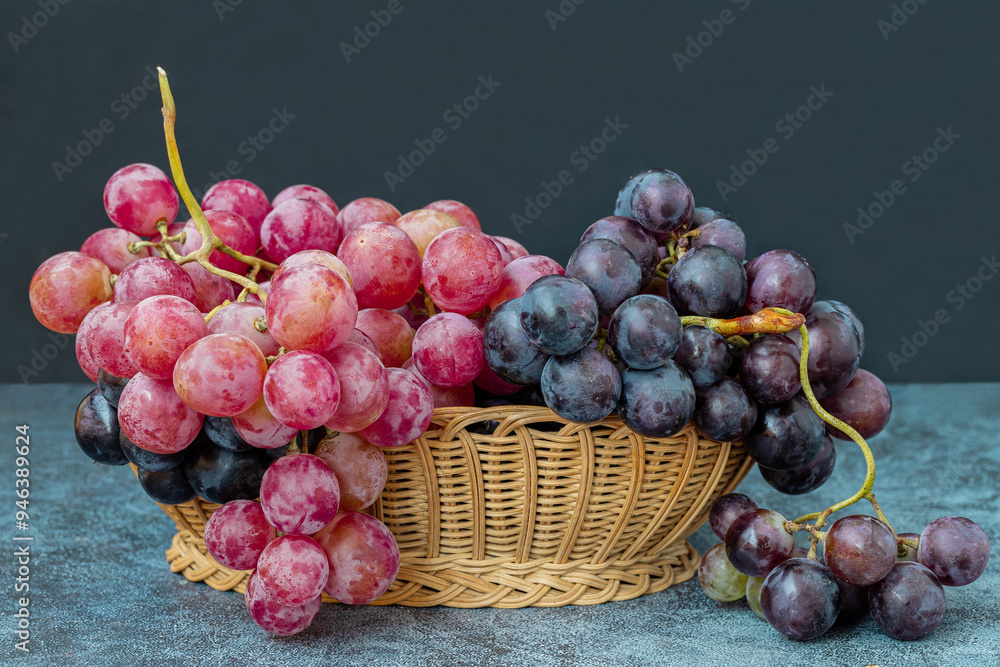 Black and red grapes in a wicker basket on a table.
