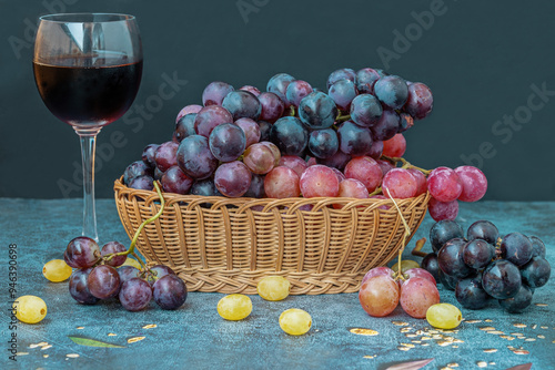 Obraz na płótnie Black grapes on a table, red grapes in a basket and a glass of red wine on the table w salonie