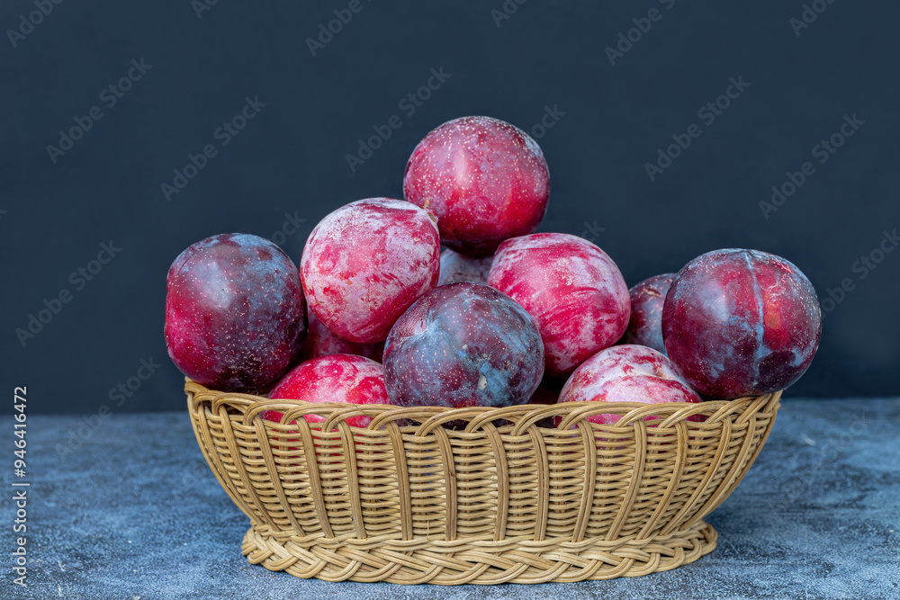Red Angelica plums in a wicker basket on the table