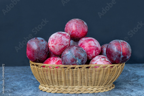 Obraz na płótnie Red Angelica plums in a wicker basket on the table w salonie