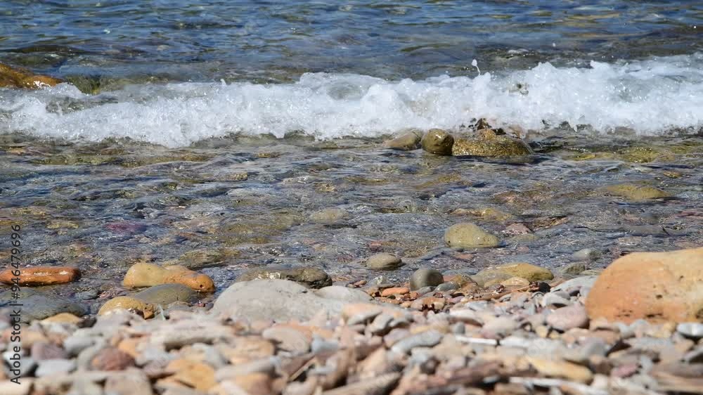 A serene lakeside view showcasing gentle waves washing over a pebble-covered shore. The focus on the water creates a soothing, natural ambiance, perfect as a backdrop in various creative projects A serene lakeside view showcasing gentle waves washing over a pebble-covered shore. The focus on the water creates a soothing, natural ambiance, perfect as a backdrop in various creative projects