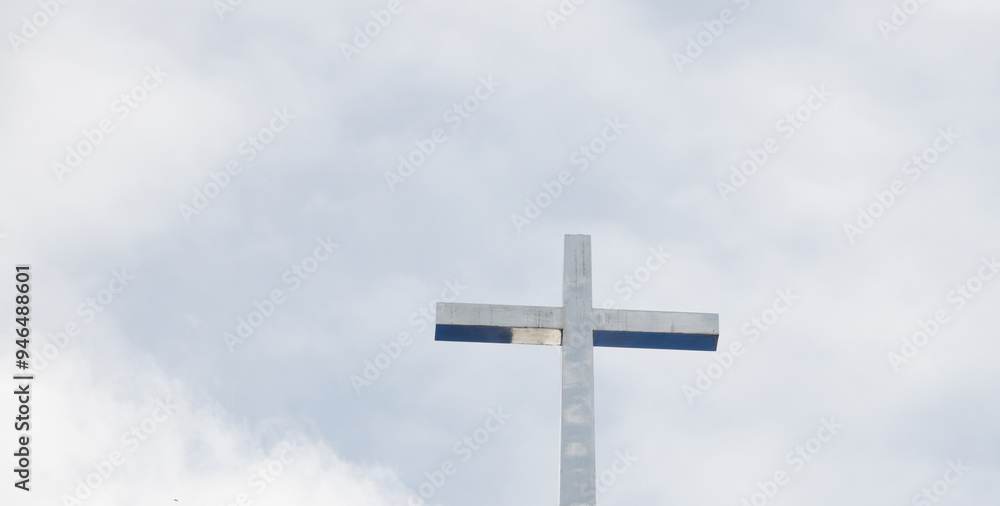 A large cross is standing tall in the sky. The sky is cloudy and the sun is not visible A large cross is standing tall in the sky. The sky is cloudy and the sun is not visible