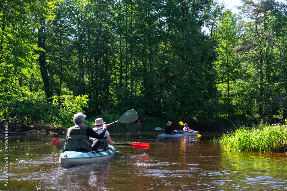 Group kayak trip for seigneur and senora . An elderly couple And adult rowing boat on the river, a water hike, a summer adventure. Age-related sports, mental youth and health, tourism, active old age Group kayak trip for seigneur and senora . An elderly couple And adult rowing boat on the river, a water hike, a summer adventure. Age-related sports, mental youth and health, tourism, active old age