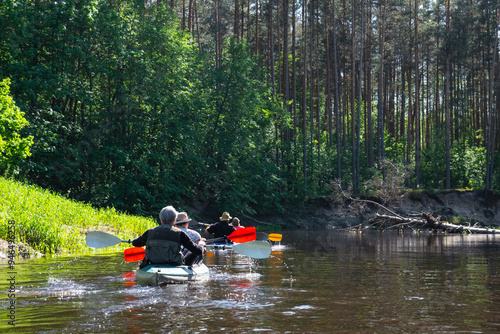 Group kayak trip for seigneur and senora . An elderly couple And adult rowing boat on the river, a water hike, a summer adventure. Age-related sports, mental youth and health, tourism, active old age photo