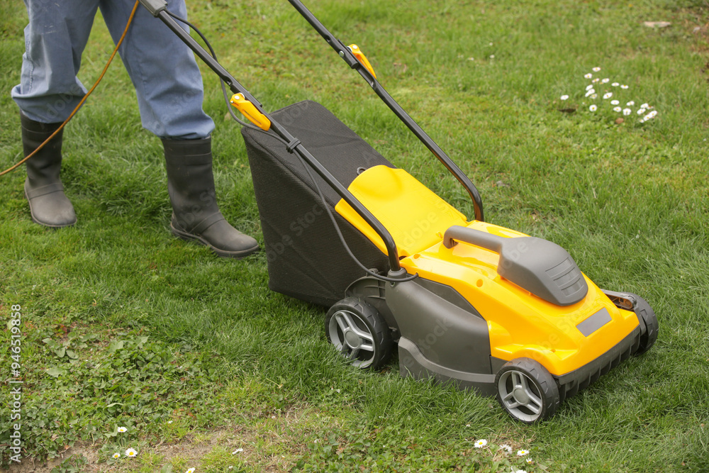 Orange lawn mower on the spring green grass in the yard Orange lawn mower on the spring green grass in the yard