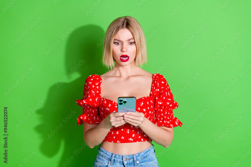 Photo of shocked confused cute girl woman wear red stylish clothes read news modern device isolated on green color background Photo of shocked confused cute girl woman wear red stylish clothes read news modern device isolated on green color background