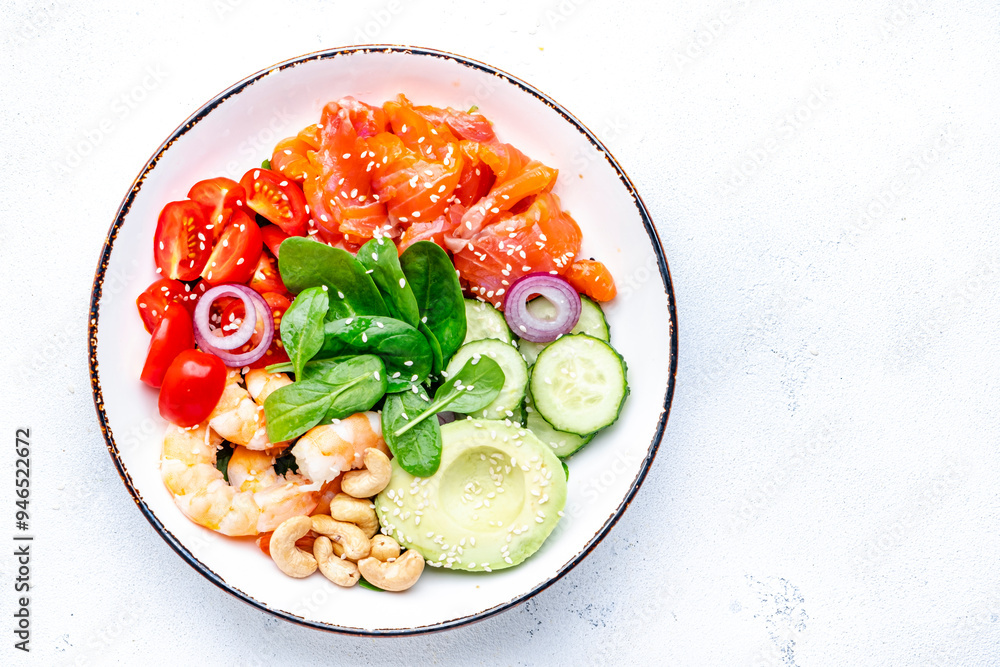 Seafood salad poke bowl with shrimp, salmon, avocado, spinach, cucumber, tomato, cashew, sesame seeds. White background, top view Seafood salad poke bowl with shrimp, salmon, avocado, spinach, cucumber, tomato, cashew, sesame seeds. White background, top view