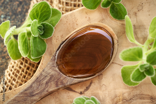 Homemade Plectranthus amboinicus syrup for common cold on a wooden spoon photo