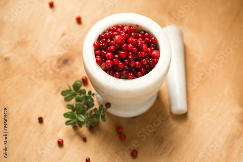 A stone mortar full of ripe wild lingonberries