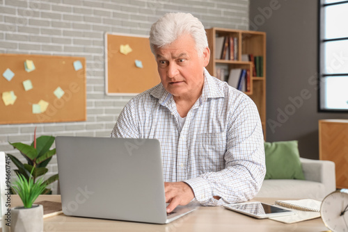 Confused senior man using l...