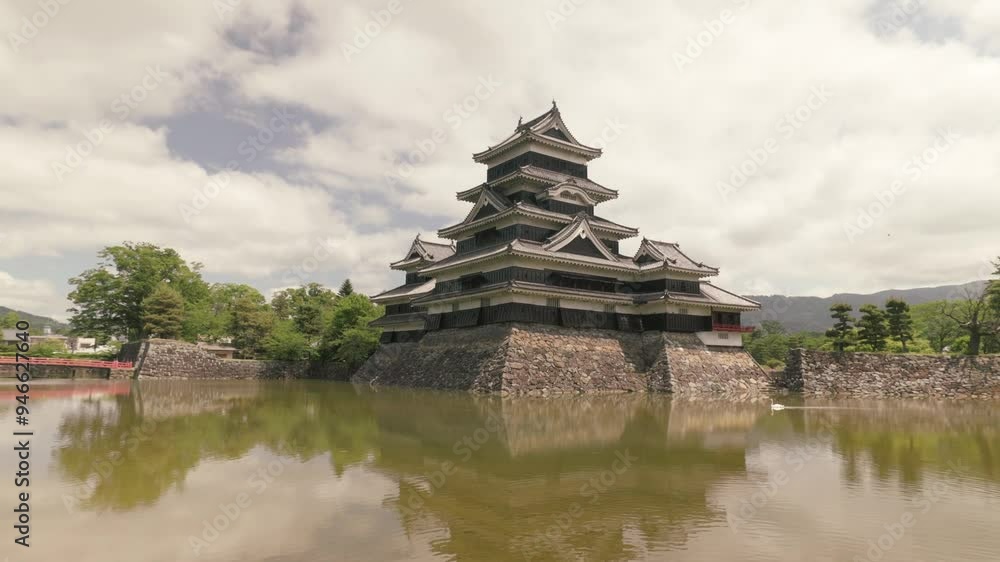 Wide shot orbit of Matsumoto Castle with the mote during midday Wide shot orbit of Matsumoto Castle with the mote during midday