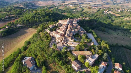 Aerial footage capturing the quaint village of Mombaroccio in the Marche region of Italy, showcasing its historic buildings, winding streets, and surrounding lush countryside photo