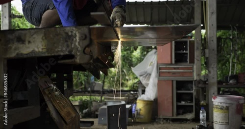 Flickering sparks of fire coming from a piece of metal that is being cut using an electric circular saw in a machine shop. photo