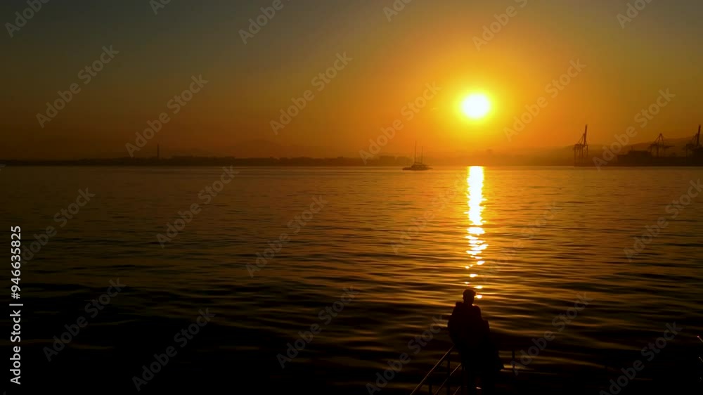 Silhouette of a person standing on a boat, watching a beautiful sunset over the calm ocean, creating a peaceful scene Silhouette of a person standing on a boat, watching a beautiful sunset over the calm ocean, creating a peaceful scene