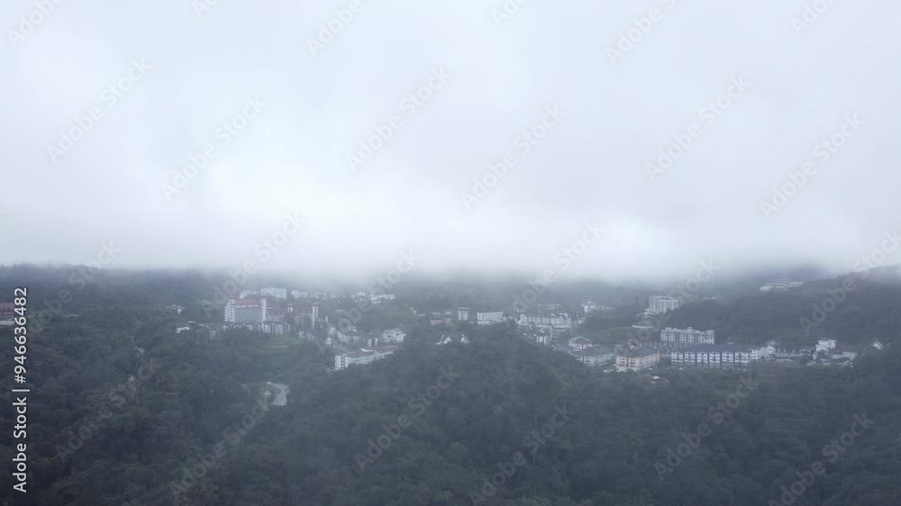 Drone shot through misty weather of forest reserve area. Buildings revealed beyond the tropical forest of Malaysia. Drone shot through misty weather of forest reserve area. Buildings revealed beyond the tropical forest of Malaysia.