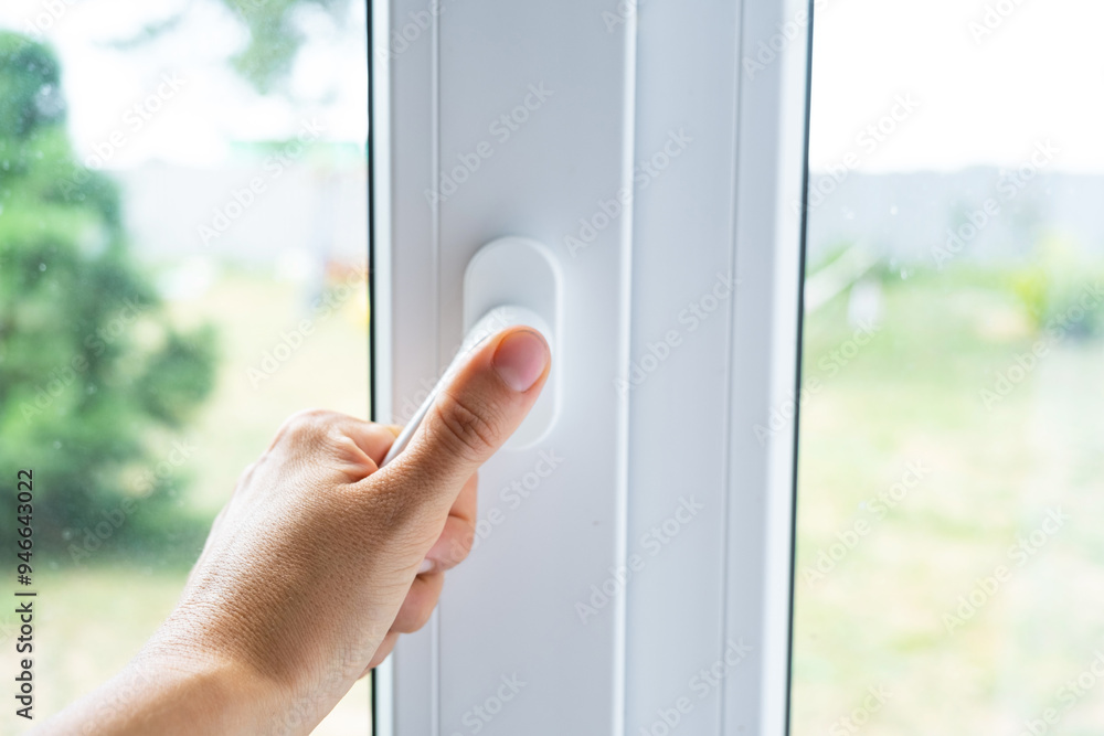 The hand holds the handle of a plastic double-glazed window, closing and opening the window with a rotary mechanism, the position of the handle for ventilation, micro-ventilation The hand holds the handle of a plastic double-glazed window, closing and opening the window with a rotary mechanism, the position of the handle for ventilation, micro-ventilation