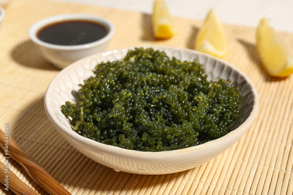 Bowl with healthy seaweed, soy sauce and lemon slices on bamboo mat, closeup Bowl with healthy seaweed, soy sauce and lemon slices on bamboo mat, closeup