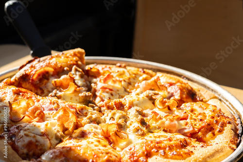 A look from above of a New York Style Pizza serving from a pan on a table with harsh sun light coming from the window photo