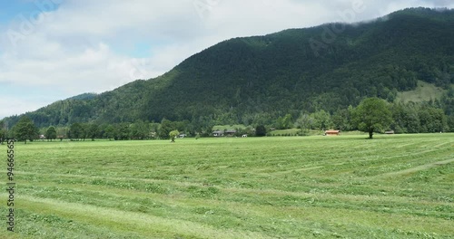 Bayerische Berglandschaft.. Grüne Weiden und Heubereitung am Fuße des Wallbergs mit Blick auf Enterrottach und das Riedersteinmassiv unter den Wolken photo