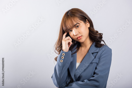 Portrait of an Asian business woman deep in thought thinking chin in her finger, pondering a question. Studio shot on white background with ample copy space, portraying her contemplative expression