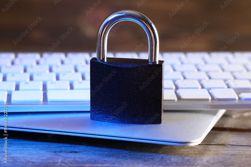 Padlock with laptop and computer keyboard on table, closeup. Cyber security concept Padlock with laptop and computer keyboard on table, closeup. Cyber security concept