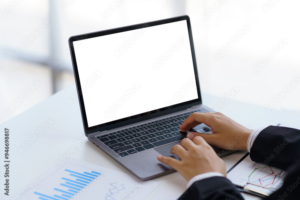 Businessman working with a laptop with an empty screen for your advertisement in an office environment Businessman working with a laptop with an empty screen for your advertisement in an office environment