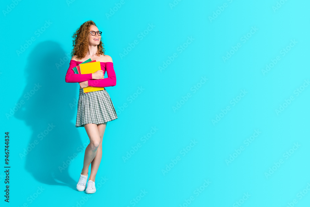 Full size photo of pretty young girl hold book look empty space wear top isolated on teal color background Full size photo of pretty young girl hold book look empty space wear top isolated on teal color background