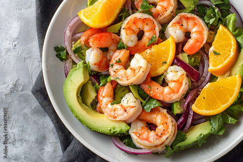 Shrimp salad with citrus fruits such as orange and grapefruit, as well as avocado, red onion and leafy greens close-up in a plate on the table. Horizontal top view from above