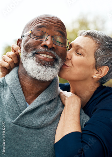 Interracial senior couple, kiss and love in park, garden or nature for kiss or care together. Happy man, woman and partner for retirement, relax and support for marriage and vacation for pensioner