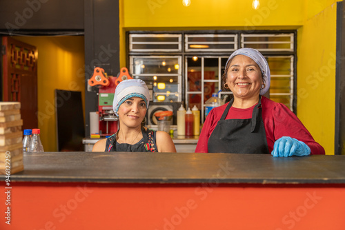 Two smiling cooks posing in their fast food restaurant kitchen