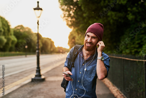 Travel, walking and portrait of man in city for music, streaming subscription and online radio. Urban town, happy and person on smartphone with earphones for listening to song, audio and podcast photo