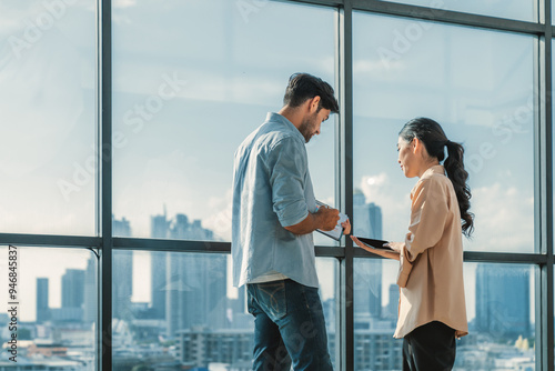 Professional businessman present financial statistic to investor while standing near panoramic window shows skyscraper or city view. Diverse businesspeople discuss about marketing plan. Tracery.