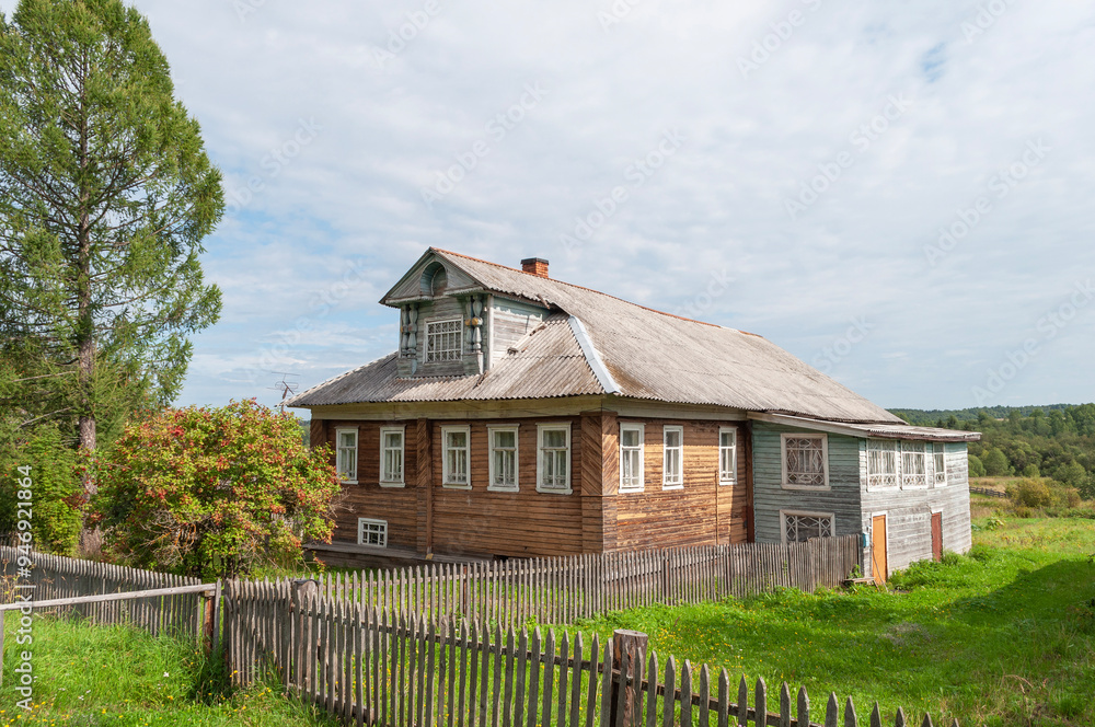 Country wooden house with a small mezzanine in northern russian village, sunny summer day Country wooden house with a small mezzanine in northern russian village, sunny summer day